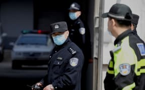 A policeman looks on as police vehicles exit the Dandong Intermediate People's Court, where the trial of Canadian businessman Michael Spavor under spying charges was held, in Dandong in China's northeast Liaoning province on March 19, 2021.