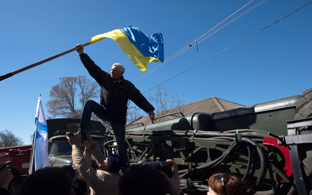 A protester pulls down a Ukrainian flag as pro-Russian forces storm a base in Novofedorivka.