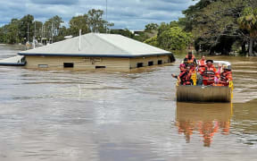 This handout photo taken on February 28, 2022 and received on March 1 from the Queensland Fire and Emergency Services shows rescuers on a boat evacuating people along a flood street around Maryborough in Queensland.