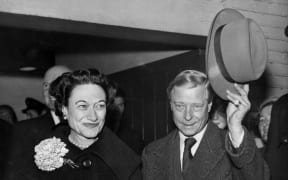 Edward, Duke of Windsor (R), with his wife the Duchess Wallis of Windsor, waves his hat to the welcoming crowd as they arrive at Victoria Station in London, from Paris, 13 November 1956. This is their first visit together to Britain since 1953.