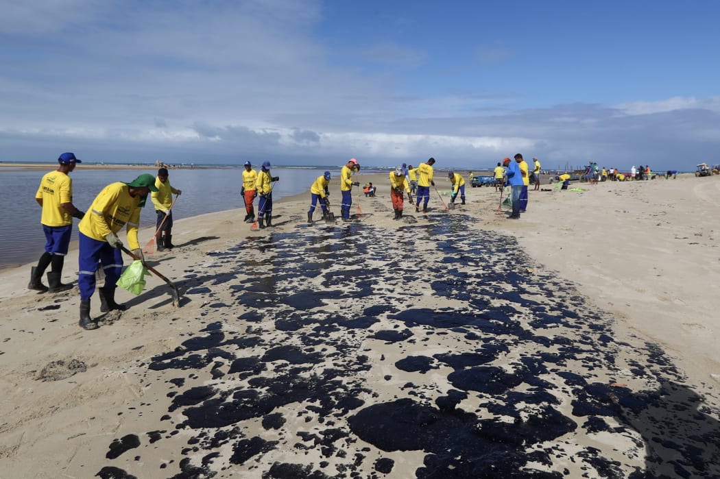 Workers remove crude oil from Carneiros Beach in Tamadare, Brazil.