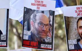(FILES) A poster portrait of hostage Nadav Popplewell is seen as relatives and supporters of Israeli captives held in Gaza since the October 7 attacks by Hamas militants, gather before the start of a four-day march to Jerusalem calling for their release, on February 28, 2024, near the site of the Supernova music festival in southern Israel. An Israeli community confirmed on June 3, 2024, the death of Israeli-British hostage Nadav Popplewell in the Gaza Strip, after Hamas militants said last month he had died of wounds. "Kibbutz Nirim announces with deep sorrow the death of abductee Nadav Popplewell in the captivity of Hamas in Gaza," the community said in a statement. (Photo by JACK GUEZ / AFP)