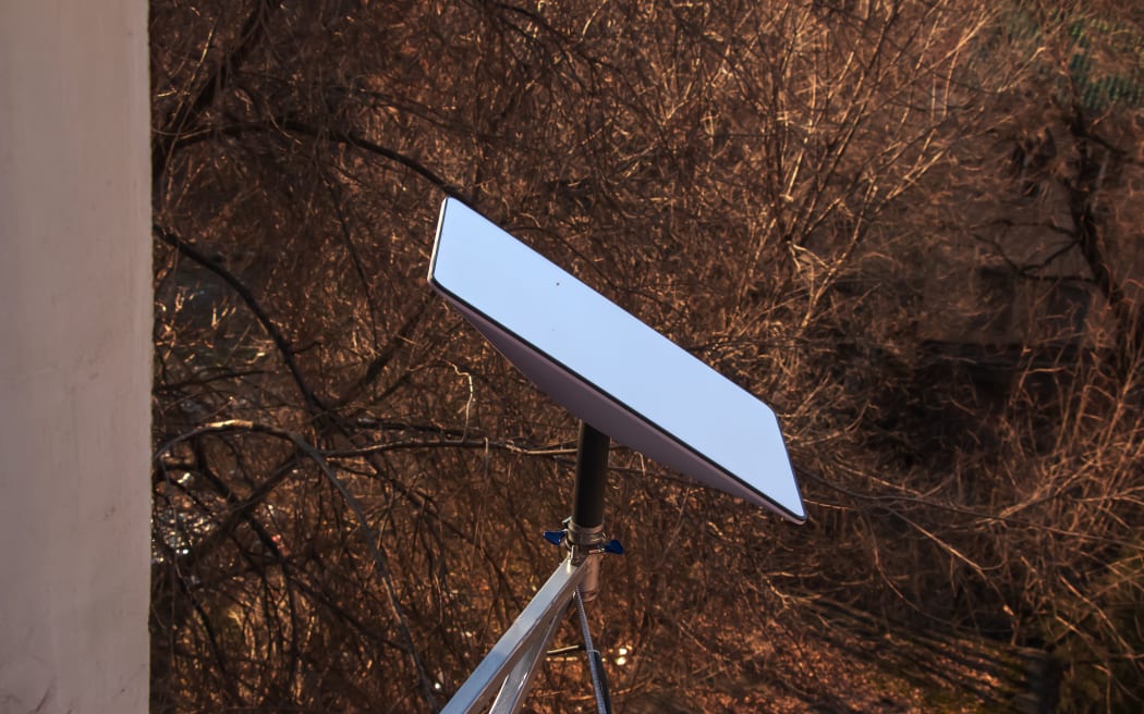 Starlink satellite dish, an internet constellation operated by SpaceX, is installed on the wall of an apartment building. View from the window of the apartment.