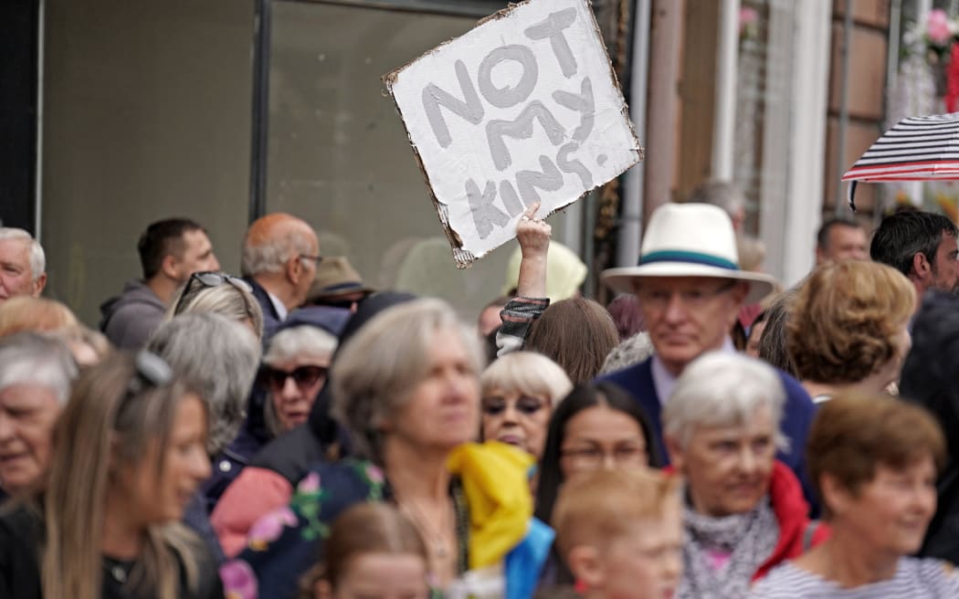 A protester holds up a "Not My King" placard in the crowd as people wait to greet King Charles III and Queen Camilla during their visit to The great Tapestry of Scotland visitor centre in Galashiels, south of Edinburgh on 6 July, 2023, to mark the 10th anniversary of the tapestry's completion.