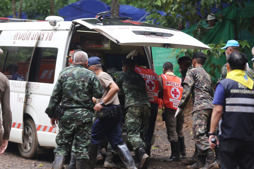 Thai soldiers and paramedics help a rescued boy on a stretcher to an ambulance outside the Tham Luang cave.