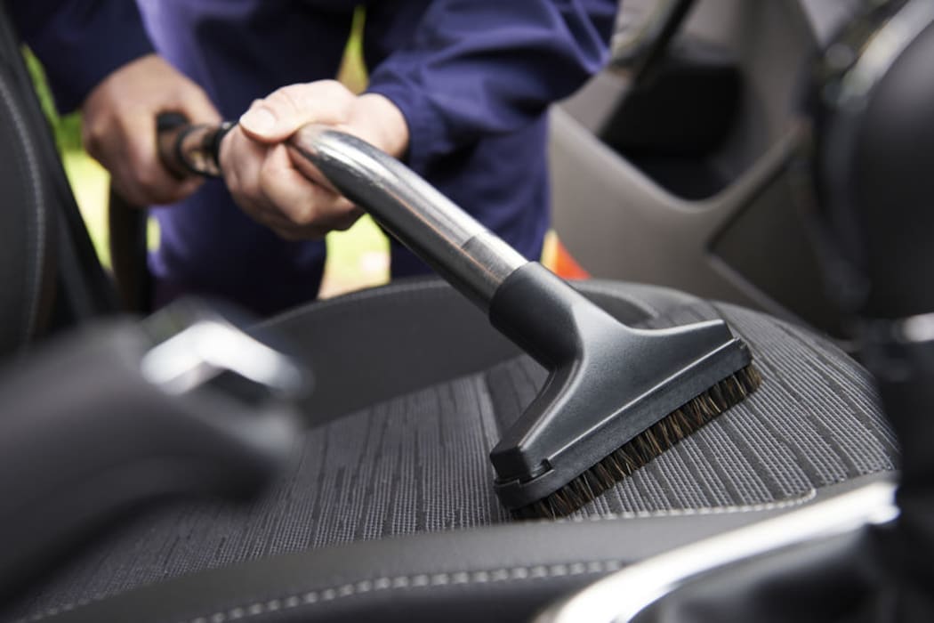 Man vacuuming car seat.