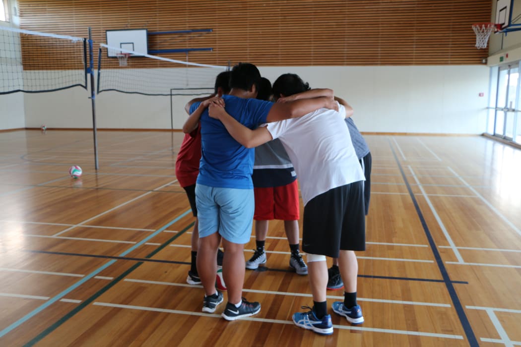 Four teenagers in sports huddle in gym