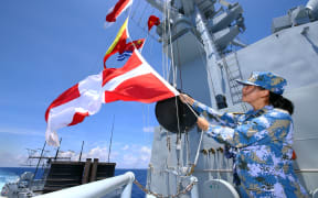 A Chinese navy soldier hangs signal flags on missile destroyer Hefei during a military exercise in the South China Sea.