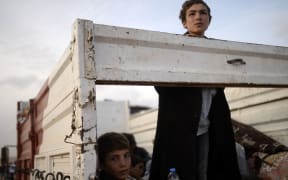 Syrian Kurds fleeing an onslaught by the jihadist Islamic State (IS) group sit in a truck as they cross the Syria Turkey border.