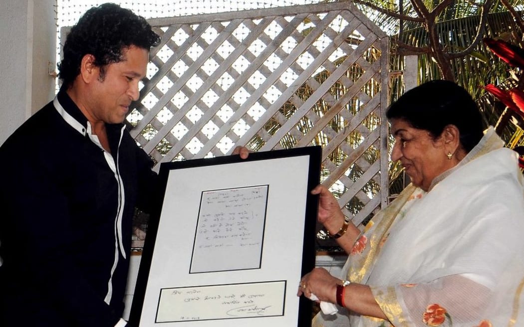 Former Indian cricketer Sachin Tendulkar (L) receives a memento from Bollywood veteran playback singer Lata Mangeshkar, who are both Bharat Ratna award recipients, during an Maharashtra Navnirman Sena event in Mumbai on March 9, 2014.