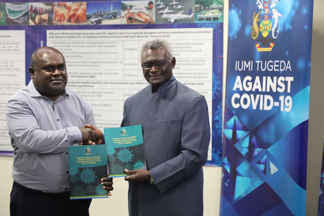 Prime Minister Manasseh Sogavare (right) hands the Economic Stimulus Package document over to the Minister of Finance and Treasury, Harry Kuma.