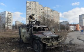 A Ukrainian Territorial Defence fighter examines a destroyed Russian infantry mobility vehicle GAZ Tigr after fighting in Kharkiv. Ukrainian forces secured full control of Ukraine's second biggest city on 27 February, 2022, following street fighting with Russian troops, the local governor said.