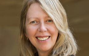 This is a head and shoulders shot of Deborah looking towards the camera and smiling. She has blonde hair and is wearing a black jacker.