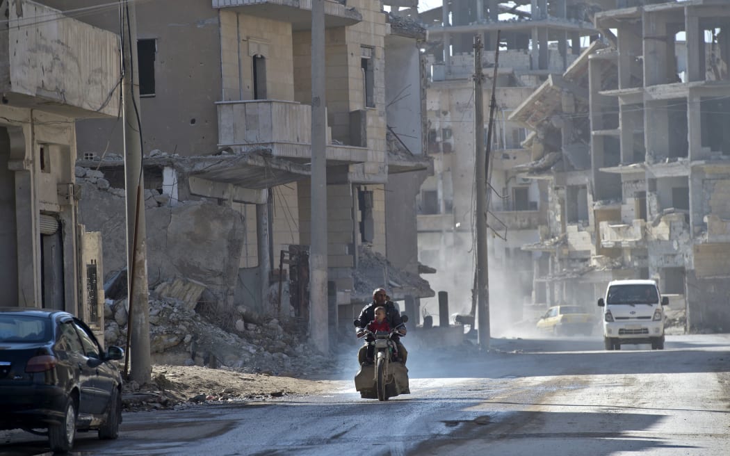 A Syrian man and a child ride a motorcycle in the Islamic State (Isis) group's former Syrian capital of Raqqa.