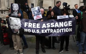 Supporters of WikiLeaks founder Julian Assange hold a banner and placards outside The Royal Courts of Justice, Britain's High Court, in central London on March 26, 2024. Two UK judges delayed a decision on whether to grant Assange a last-ditch appeal against extradition to the United States, giving Washington three weeks to provide "assurances" in the case. (Photo by Daniel LEAL / AFP)