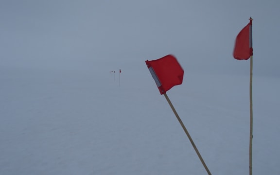 Small flags mark the safe route to walk during a white-out on the sea ice in front of Scott base, Antarctica.