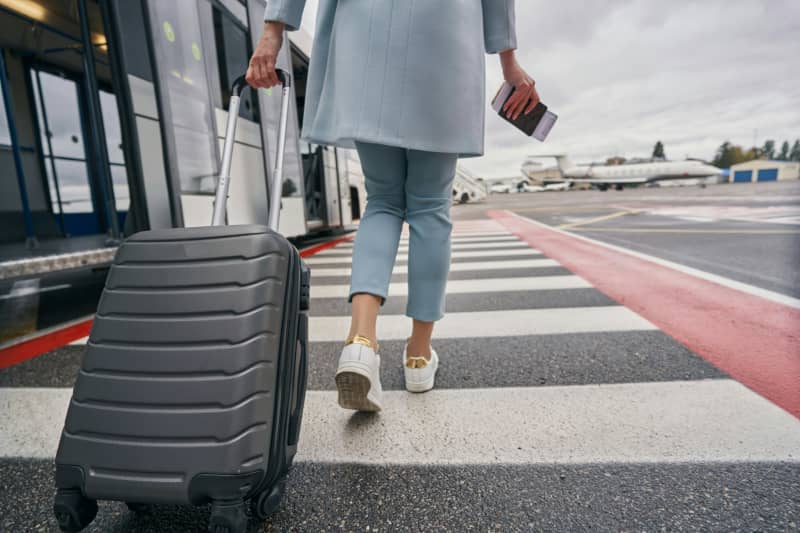 Woman at the airport with her suitcase and passport.