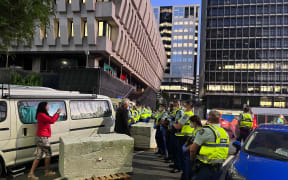 Police and protesters in front of concrete barriers