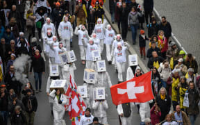 Protesters hold flags and banners during a protest in Lausanne, western Switzerland, against the country's current measures to tackle the spread of the coronavirus.
