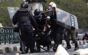 Police carry a colleague injured by a grenade thrown into their ranks.