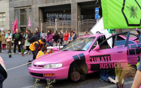 Extinction Rebellion protesters have blocked off Stout St in central Wellington, in a bid to cause disruptions outside MBIE's office.