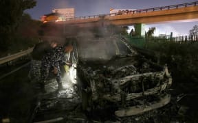 Lebanon policemen inspect the burnt remains of a UNIFIL vehicle, on the road leading to Beirut’s international airport on 14 February, 2025.