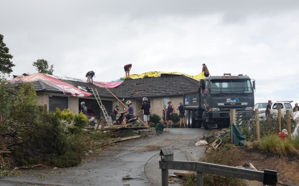 Residents race to get tarps over houses that lost their roofs in the tornado in Mangawhai, 26 January 2025.