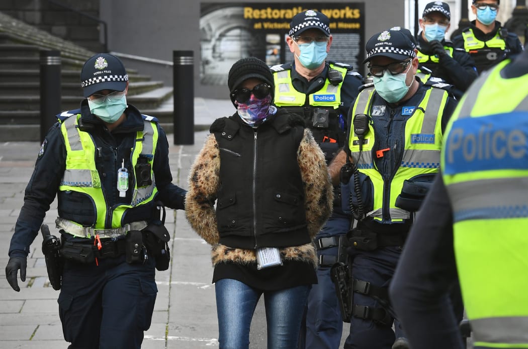 Police detain a protester (c) at a proposed anti-lockdown rally which failed to materialize in Melbourne on August 9, 2020.