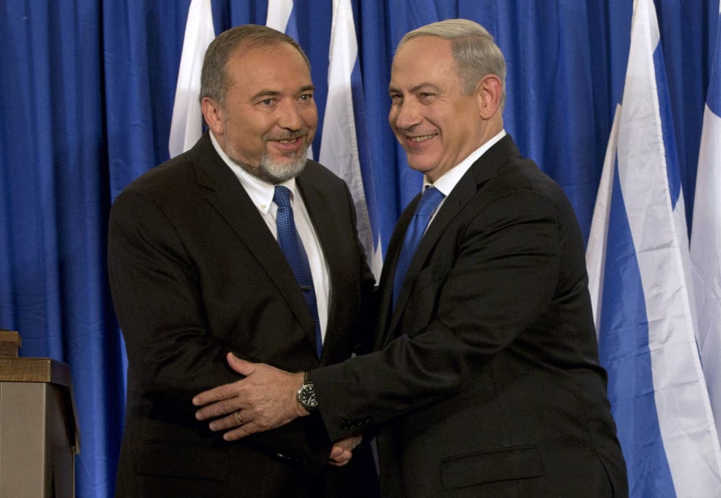 FILE - In this Oct. 25, 2012 file photo, Israeli Prime Minister Benjamin Netanyahu, right, and former Israeli Defense Minister Avigdor Lieberman shake hands in front of the media