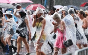 Fans of US singer Taylor Swift, also known as a Swifties, shelter from the rain as they arrive for Swift's concert in Sydney on February 23, 2024. (Photo by DAVID GRAY / AFP)