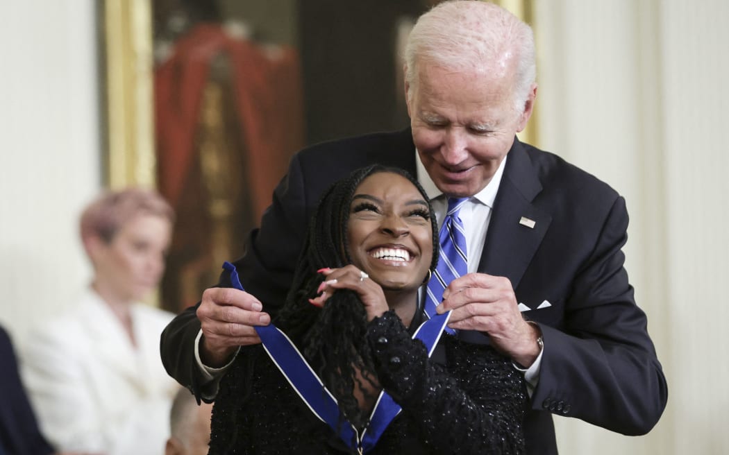 WASHINGTON, DC - JULY 7: U.S. President Joe Biden presents the Presidential Medal of Freedom to Simone Biles, Olympic gold medal gymnast and mental health advocate, during a ceremony in the East Room of the White House July 7, 2022 in Washington, DC. President Biden awarded the nation's highest civilian honor to 17 recipients. The award honors individuals who have made exemplary contributions to the prosperity, values, or security of the United States, world peace, or other significant societal, public or private endeavors.   Alex Wong/Getty Images/AFP (Photo by ALEX WONG / GETTY IMAGES NORTH AMERICA / Getty Images via AFP)