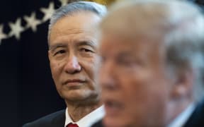 China's Vice Premier Liu He looks on as US President Donald Trump speaks.