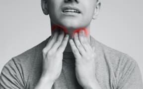 Man with thyroid gland problem, touching his neck.