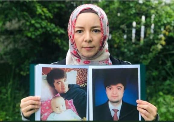 Rizwangul NurMuhammed holding photos of her brother, Maiwulana- detained in Xinjiang for the past four years.