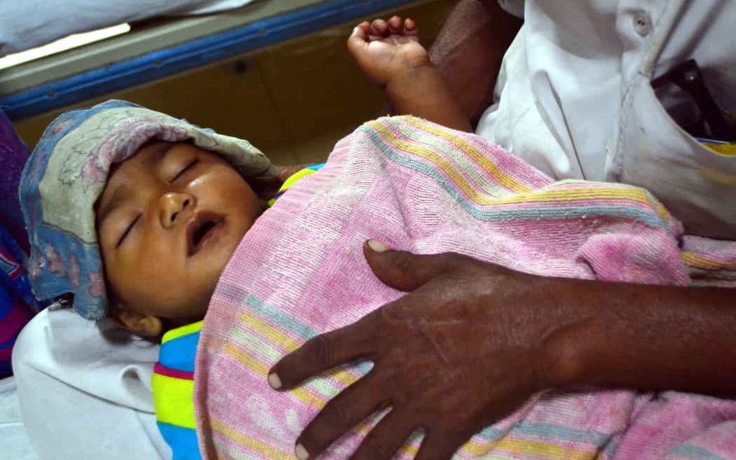 An Indian man holding his baby suffering from malaria at an emergency ward at a children's hospital in Allahabad. September 3, 2015.