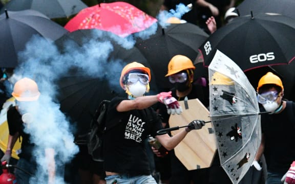 A protester throws back a round of tear gas fired by the police during a demonstration in the district of Yuen Long in Hong Kong on July 27, 2019.