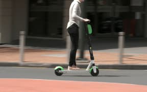 Person riding a Lime scooter in Auckland city.
