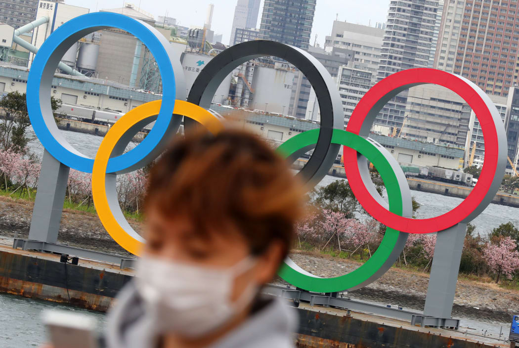 A woman wearing a mask walks near the Olympics' mark in Odaiba, Tokyo on February 22, 2020, amid the outbreak of a new coronavirus in Japan.