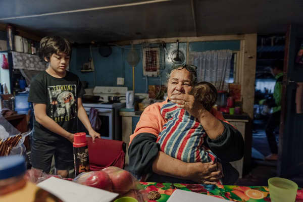 Carol Teepa in her kitchen in Ruatoki, with her youngest grandchild, Mia, and her whāngai son, Wanea.
