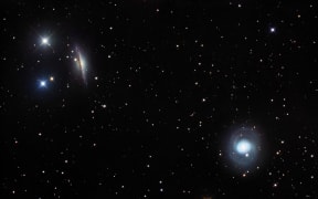 Galaxies NGC 1055 and M77, optical image. The galaxies NGC 1055 and M77 are seen edge-on (upper left) and face-on (lower right) respectively. NGC 1055's disc is seen as a dark band of dust crossing the brighter central bulge while the spiral arms are visible in M77. Both NGC 1055 and M77 are active galaxies that emit radiation from their nucleus, which ionises the gases in them and releases the light that makes them glow. Both galaxies lie about 50 million light years from Earth but are about 400 thousand light years apart from each other. They are found in the constellation Cetus. (Photo by ROBERT GENDLER/SCIENCE PHOTO LIB / RGN / Science Photo Library via AFP)