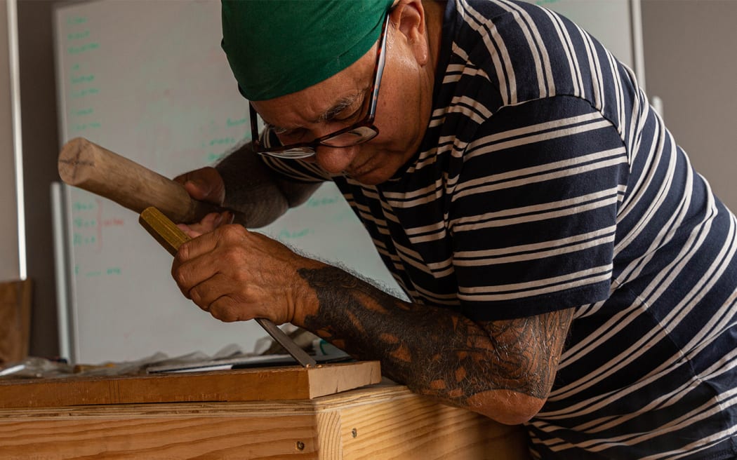 Master carver James Rickard carves a design into a piece of wood