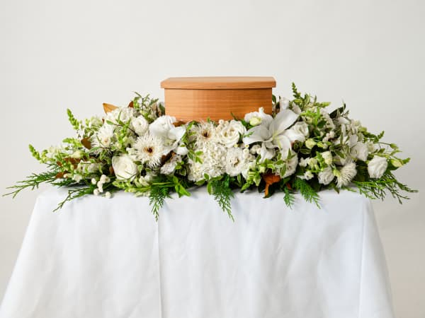 Flowers on a table with cremation urn of ashes.