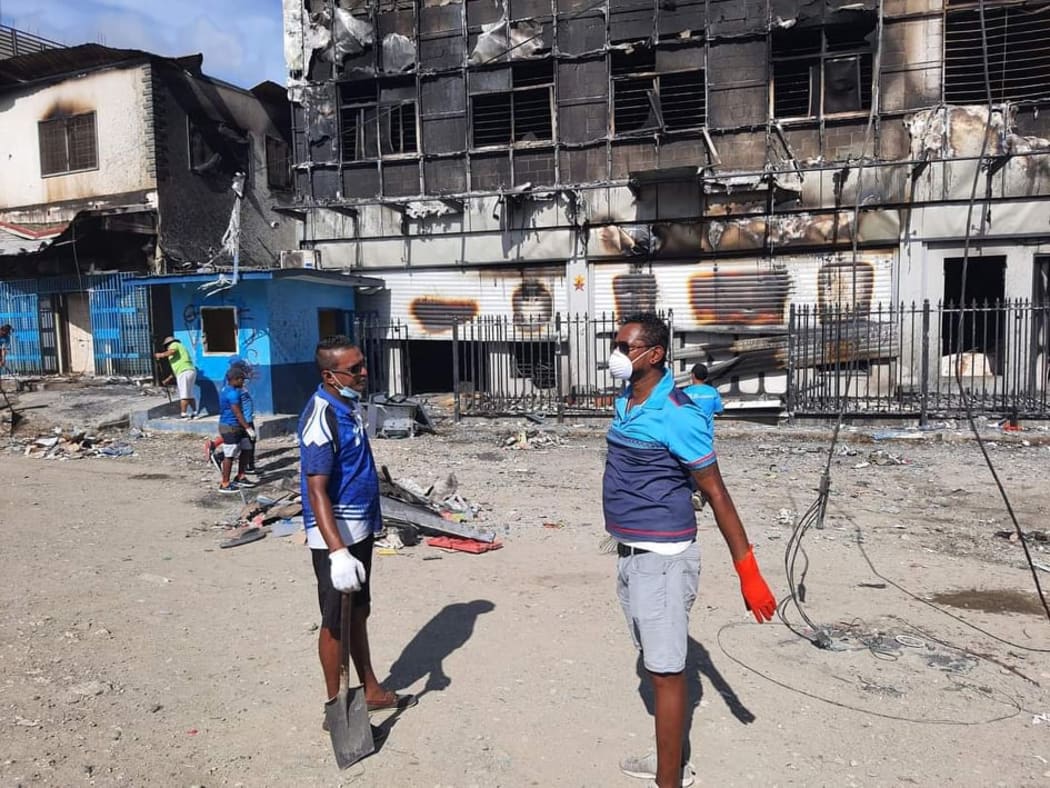 Members of the Fijian community in Honiara help BSP staff clean up. The bank was one of nearly 60 businesses torched by protesters last week.