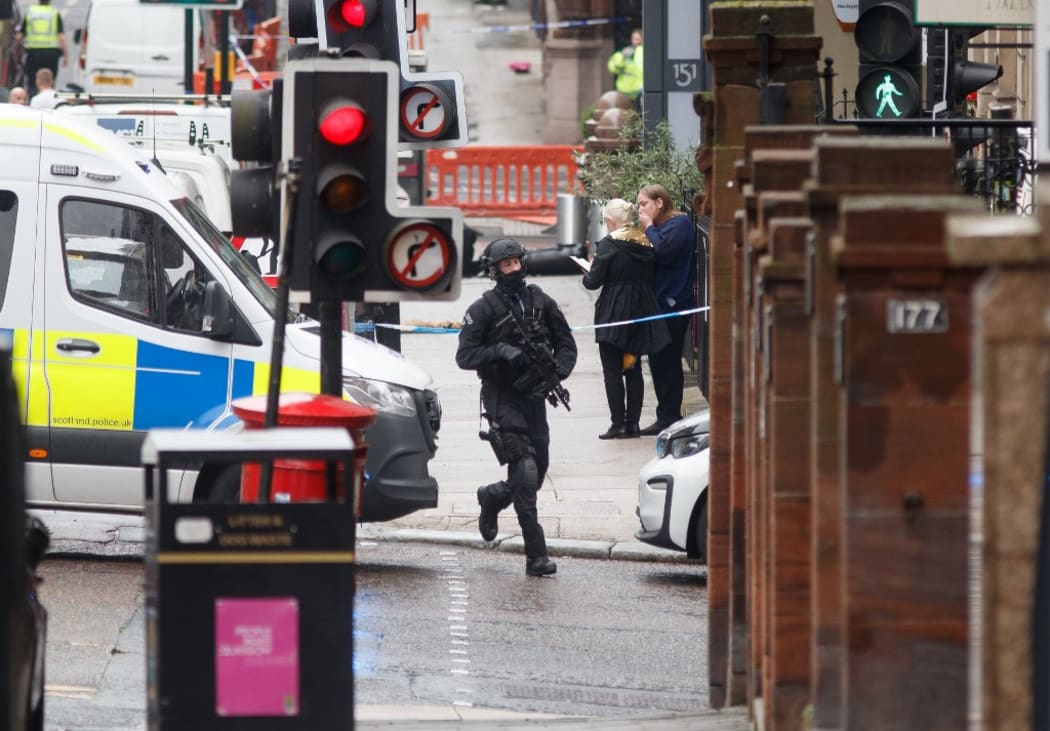 An armed specialist police officer runs as he responds at the scene of a fatal stabbing incident at the Park Inn Hotel in central Glasgow on June 26, 2020.