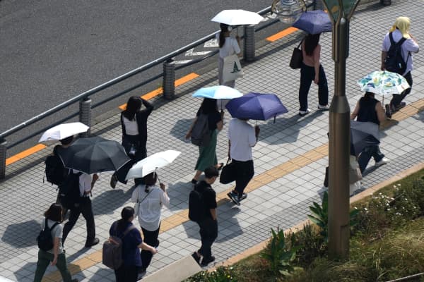 People with umbrellas walk in the scorching sun in Tokyo on September 1, 2025.