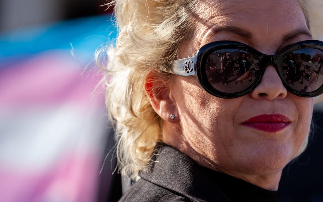 Anti-transgender activist Posie Parker with a trans flag in the background.