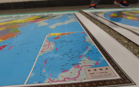 In this photo taken on June 15, 2016 a vendor stands behind a map of China including an insert with red dotted lines showing China's claimed territory in the South China Sea, in Beijing.