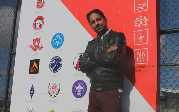 Man in leather jacket stands by club board