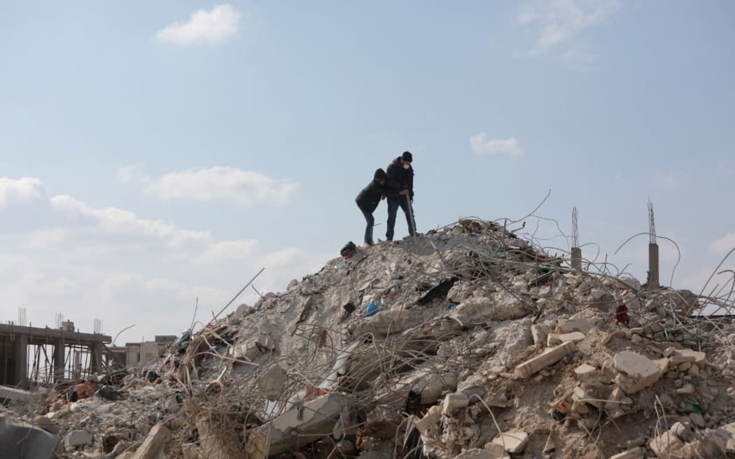 A Syrian man and boy inspect the rubble of a building in the town of Jindayris, in the rebel-held part of Syria's Aleppo province on February 11, 2023, days after a deadly earthquake hit Turkey and Syria. (Photo by Bakr ALKASEM / AFP)
