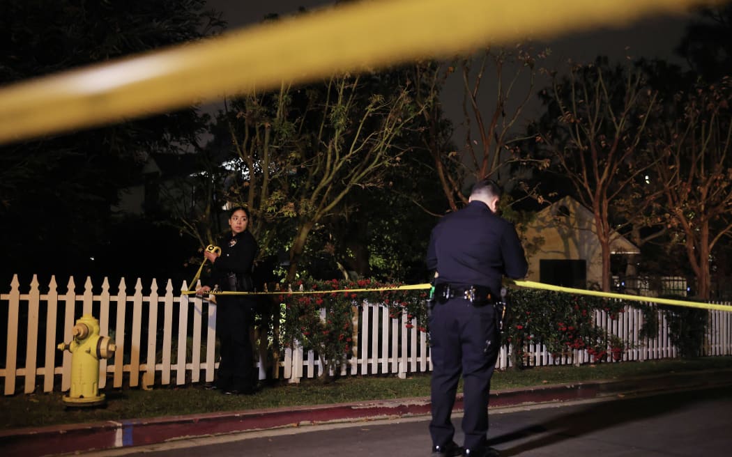 LAPD officers put up police tape as the police investigate two people found dead in Rob Reiner's home on Sunday, in Brentwood, California.